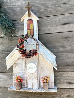 a white church with a wreath on the top and two small pots in front of it