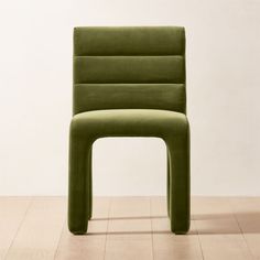 a green chair sitting on top of a hard wood floor next to a white wall