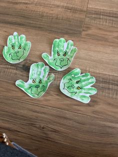 three green handprints on top of a wooden table