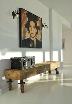 a wooden bench sitting in the middle of a room with pictures hanging on the wall