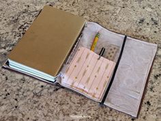 an open notebook sitting on top of a table next to a pen and paper bag