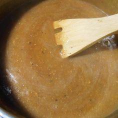 a wooden spoon in a pot filled with brown liquid