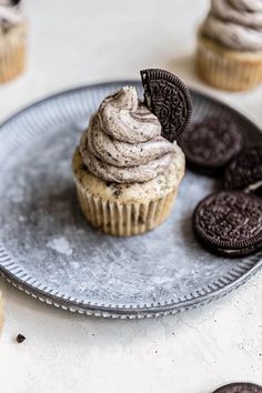 an oreo cookie cupcake with frosting on a plate next to some cookies