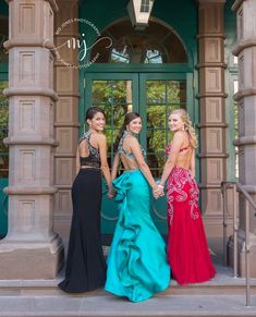 three beautiful women standing in front of a building holding hands and posing for the camera