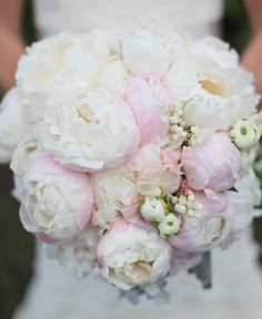 a bride holding a bouquet of white and pink flowers