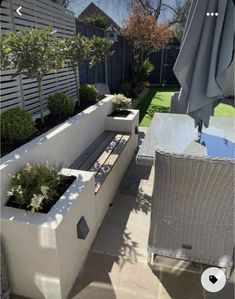 an outdoor seating area with potted plants and umbrellas in the back yard on a sunny day