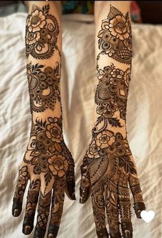 two hands with henna tattoos on them, one is showing off the intricate design