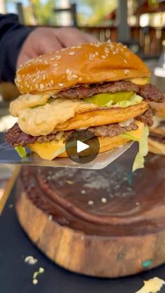 a hamburger being cut in half on top of a wooden cutting board with a knife