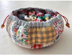 a close up of a bag filled with different colored thread and spools on a white surface