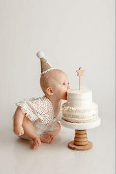 a baby with a party hat sniffing a cake