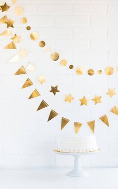 a white cake with gold foil stars on it and a bunt banner in the background