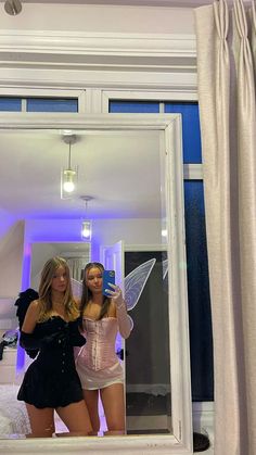 two beautiful young women standing in front of a mirror