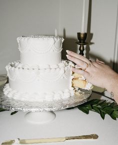 a white wedding cake sitting on top of a table next to a knife and fork