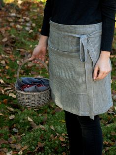 a woman is holding a basket with berries in it and standing on the grass outside