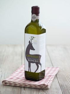 a bottle of olive oil sitting on top of a table next to a napkin with a red and white checkered cloth