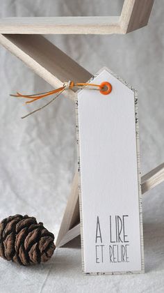 a pine cone is sitting next to a wooden frame with a tag on it that says, a liee et pelier