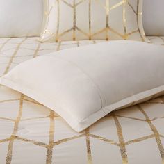 a bed with white and gold sheets and pillows