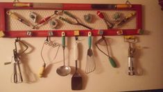 a red rack with utensils hanging from it's sides on a wall