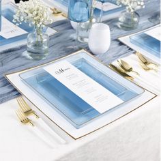 the table is set with blue and white place settings, silverware, and flowers