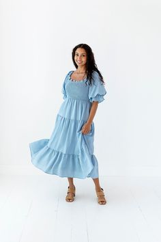 Features Square neck Elbow length elastic sleeve Smocked bodice Pockets Lined 97% Polyester, 3% Spandex Size + Fit Small 0-4, Medium 4-8, Large 8-12 Kristin is 5'4" a size 3 and is wearing a size Small True to size. Size Bust Length Small 41" Medium 41" Large 41" Flowy Smocked Dress With Square Neck And Smocked Bodice, Flowy Smocked Dress With Bodice And Square Neck, Billowy Square Neck Smocked Dress, Flowy Smocked Top With Puff Sleeves, Billowy Smocked Bodice Dress For Summer, Flowy Smocked Puff Sleeve Top, Flowy Smocked Dress With Short Elastic Sleeves, Billowy Smocked Bodice Dress, Flowy Puff Sleeve Smocked Top