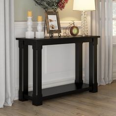 a black table with a lamp and pictures on it next to a window sill