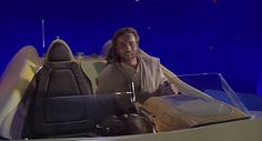 a man sitting on top of a boat with luggage in the back and an airplane flying overhead