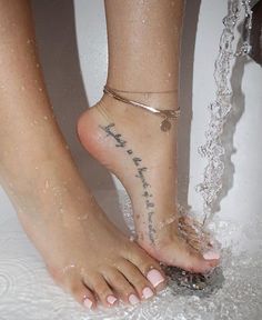 a woman's feet in the water with words written on her ankles and ankle