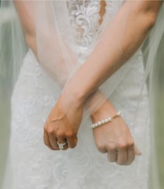 a woman in a wedding dress holding her hand out to the side while wearing a ring