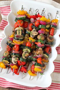 a white platter filled with assorted veggies on skewers