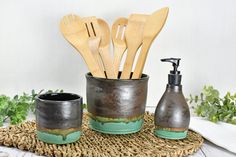 wooden utensils and soap dispenser on woven place mat next to plant