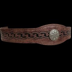 a brown belt with a metal buckle on it's side and an intricate design