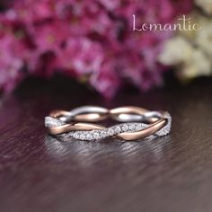 a wedding band with two rows of diamonds on top of a wooden table next to flowers