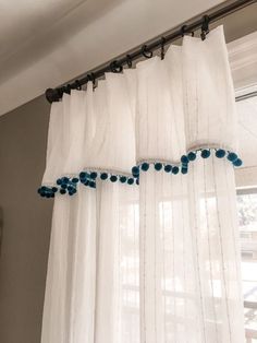 white curtains with blue pom poms hanging from them