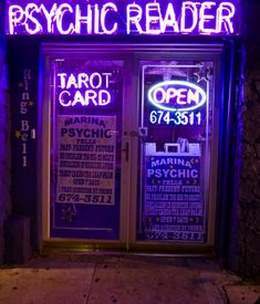 the psychic reader is lit up in purple and blue neon lights on the front door