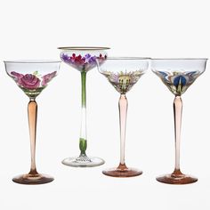 three wine goblets with different designs on them, one is empty and the other has flowers in it