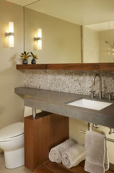 a bathroom with a sink, toilet and towel rack on the counter next to it