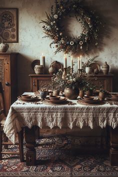 a dining room table is set with dishes and candles on it, surrounded by wreaths