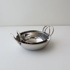 two metal bowls with handles on a white table