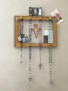 a wooden frame with beads and pictures hanging from it's sides on the wall