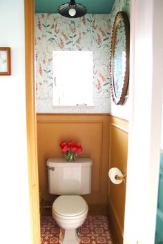 a small bathroom with a toilet and flower pot on the floor in front of it