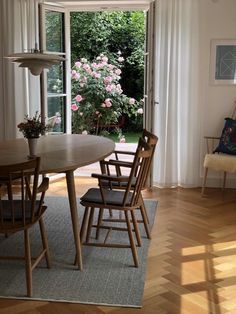 a dining room table with four chairs in front of an open door to a garden