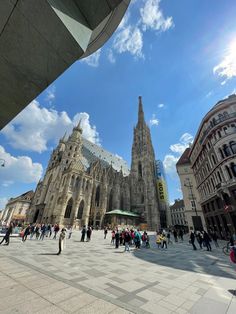 people are walking around in front of a large building with many windows and spires