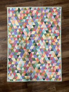 a multicolored quilt on a wooden floor