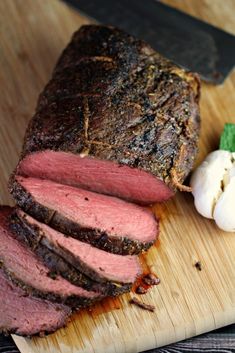 the meat is sliced and ready to be served on the cutting board with garlic next to it