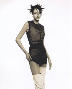 a woman in short shorts and knee high boots posing for the camera with her hands on her hips