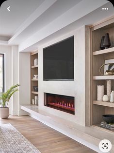 a living room with a large tv mounted on the wall and a fire place in front of it