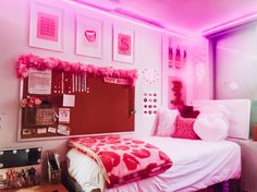 a bedroom with pink lighting and pictures on the wall