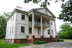 an old white house with columns on the front and second story is shown in this image