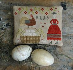 two white eggs sitting on top of a wooden floor next to a pillow and some grass