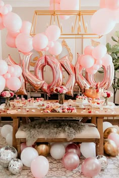 a table topped with balloons and pink letters